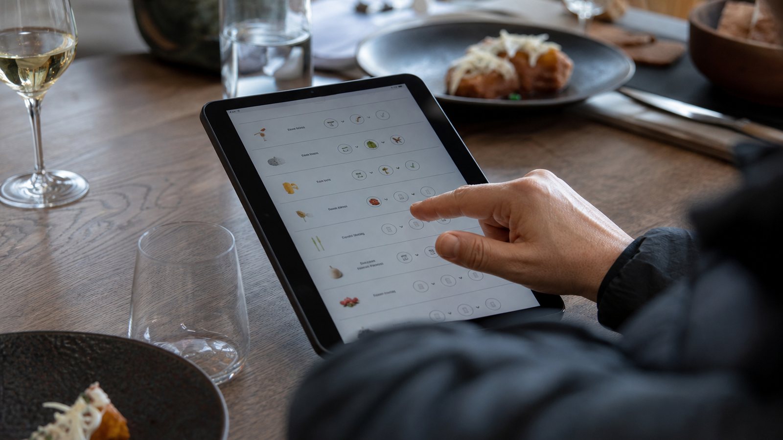 Membre de l'équipe consultant les allergènes d'un plat sur une tablette en salle